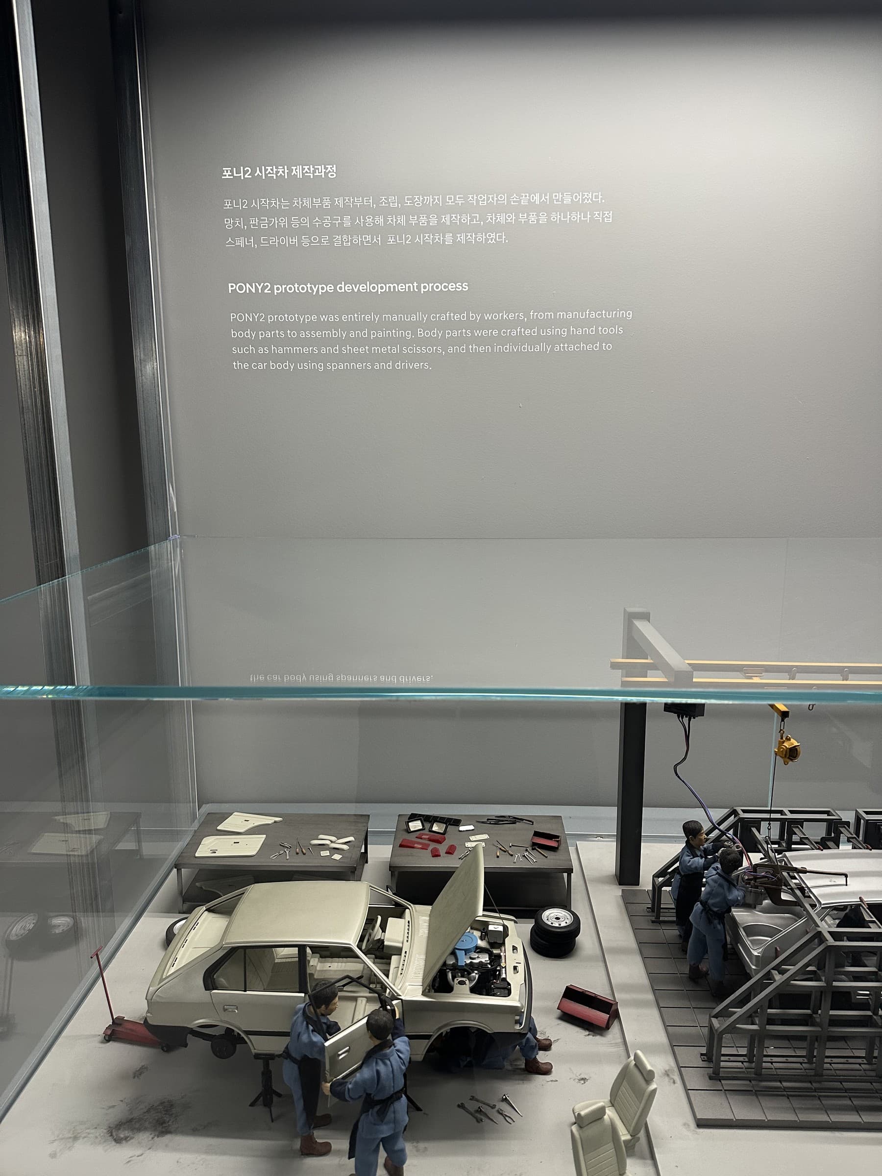 A display with scale models and a bilingual description of the manual production process for the Pony2 prototype