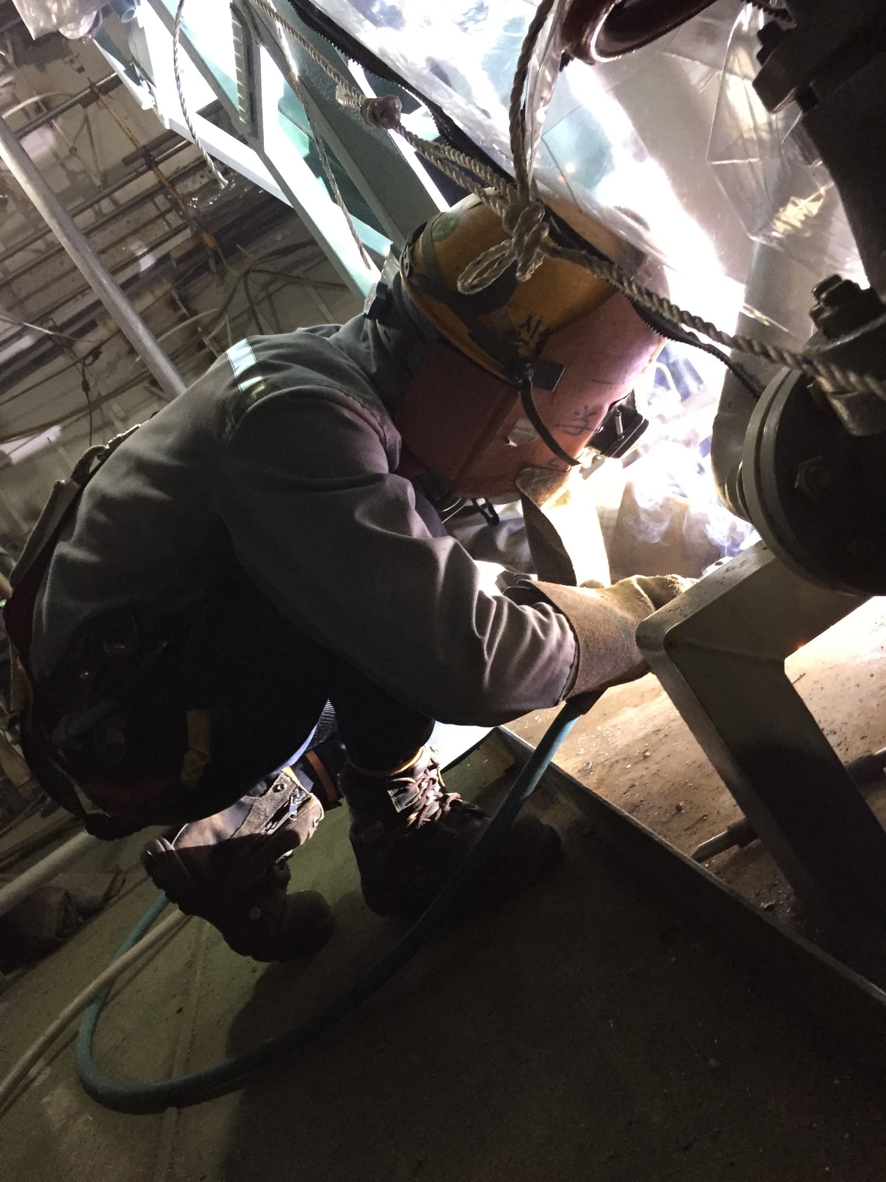 A worker in protective equipment welding inside a steel structure